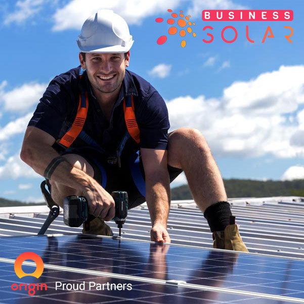 Man installing commercial solar panels on roof of building on behalf of Business Solar, a proud partner of Origin Energy
